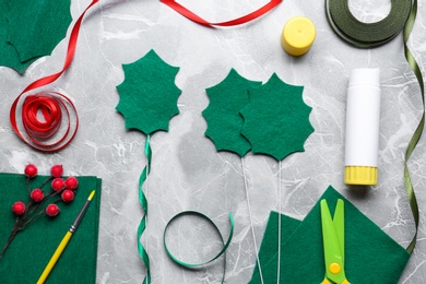 Photo of Set of instruments and materials for making mistletoe branch on grey table, flat lay