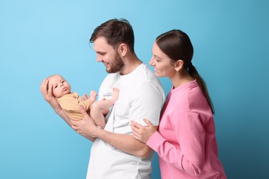 Photo of Happy family. Parents with their cute baby on light blue background