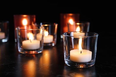 Burning candles on table in darkness, space for text. Funeral symbol