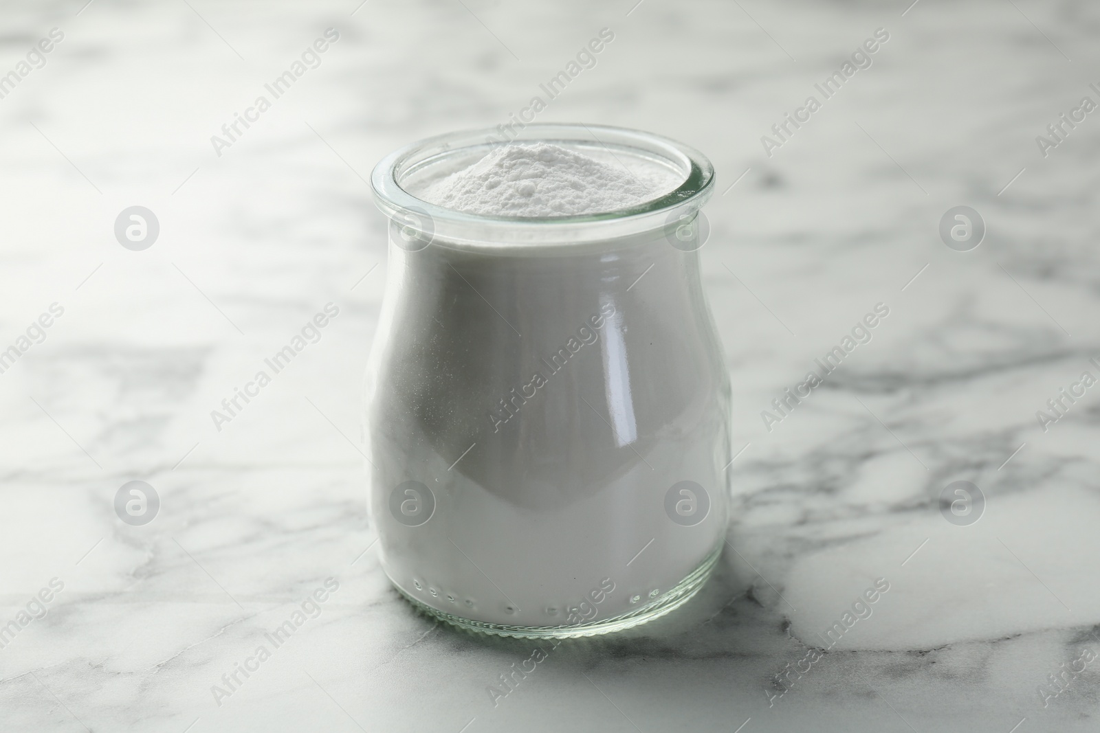 Photo of Baking powder in jar on white marble table