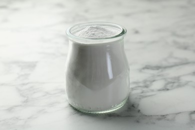 Photo of Baking powder in jar on white marble table