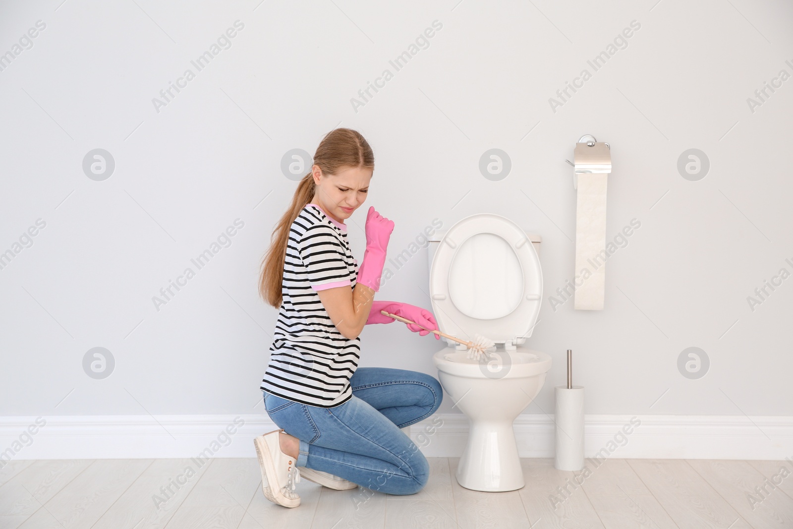 Photo of Woman cleaning toilet bowl in bathroom