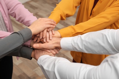 Photo of Young people putting their hands together indoors, closeup