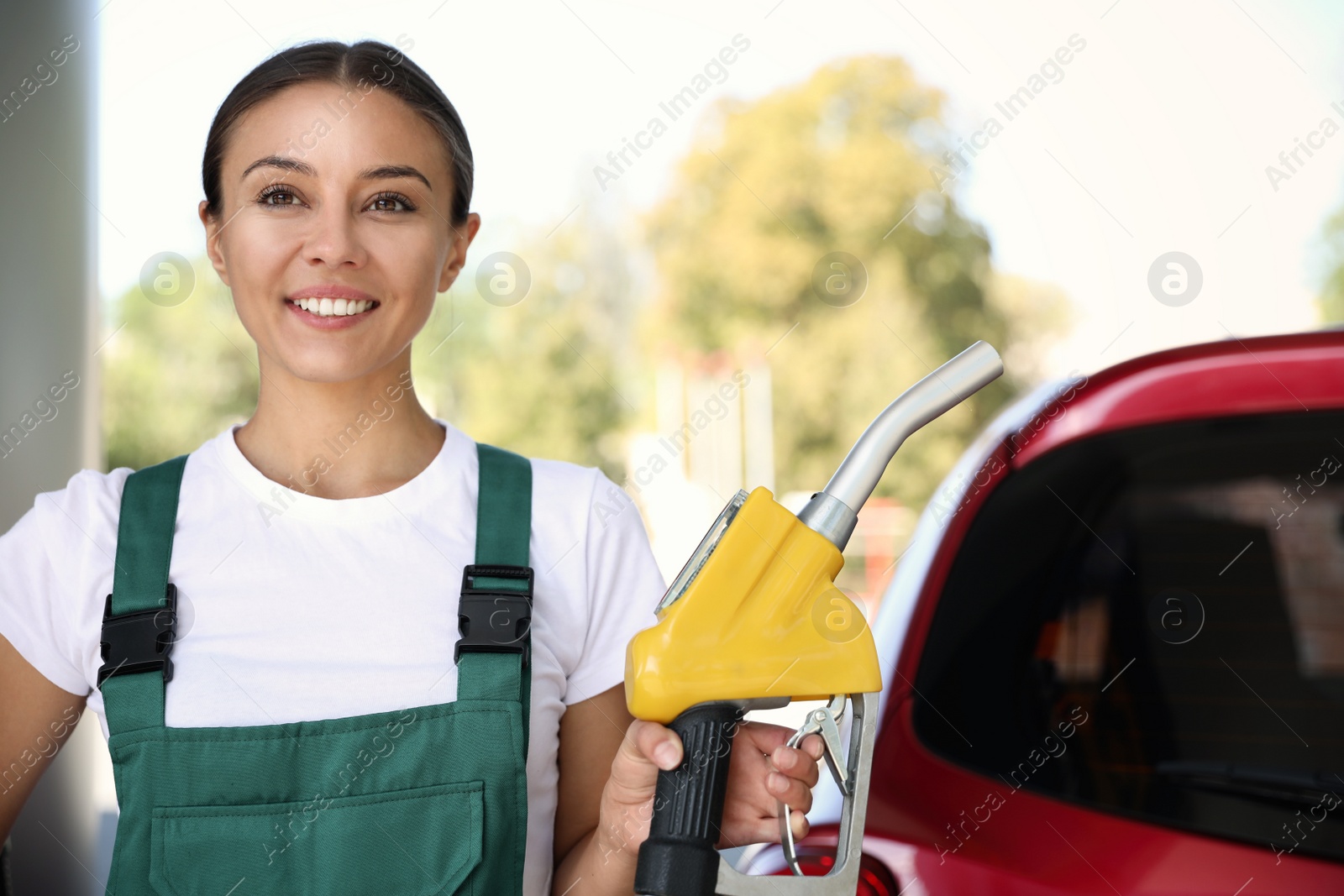 Photo of Young worker with fuel pump nozzle near car at modern gas station