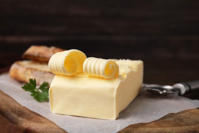 Photo of Tasty butter, slices of bread and spoon on wooden table, closeup