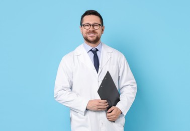 Photo of Smiling doctor with clipboard on light blue background