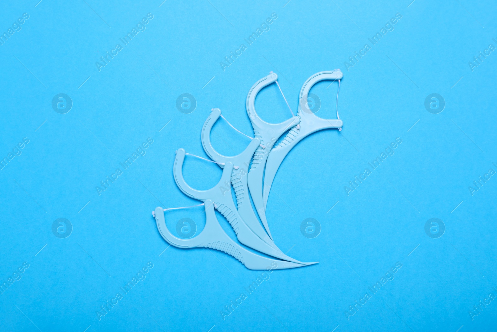 Photo of Dental flossers on light blue background, flat lay