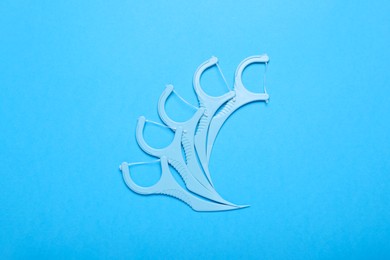 Dental flossers on light blue background, flat lay