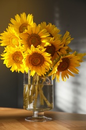 Photo of Bouquet of beautiful sunflowers in vase on table indoors