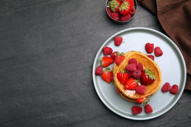 Photo of Tasty pancakes served with honey and berries on black table, flat lay. Space for text