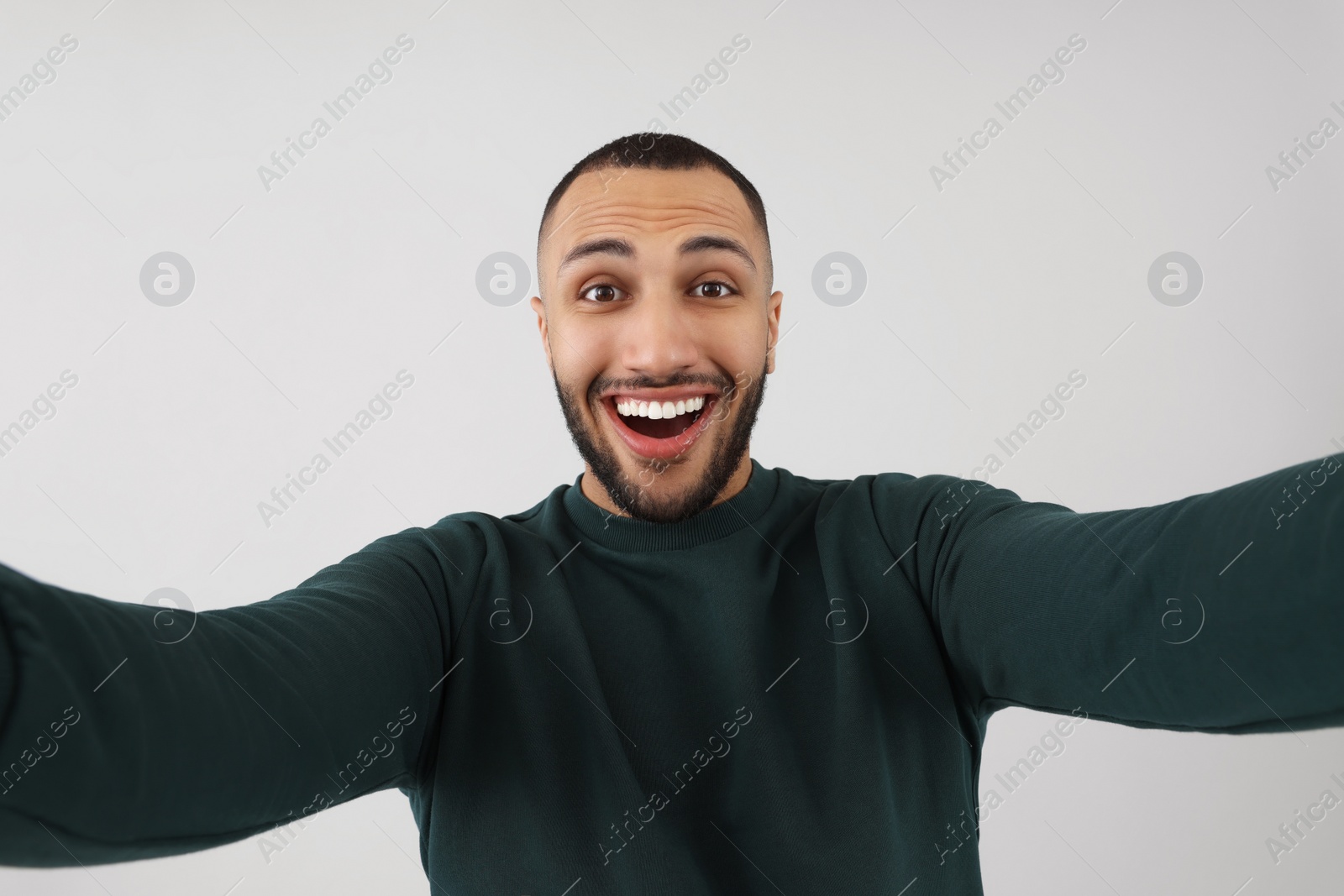 Photo of Smiling young man taking selfie on grey background