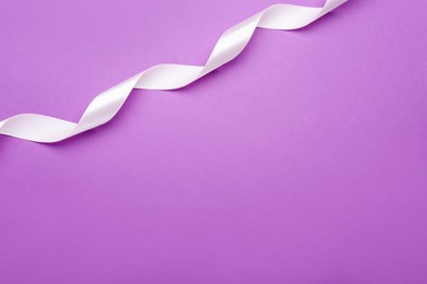 Photo of Beautiful white ribbon on purple background, top view. Space for text