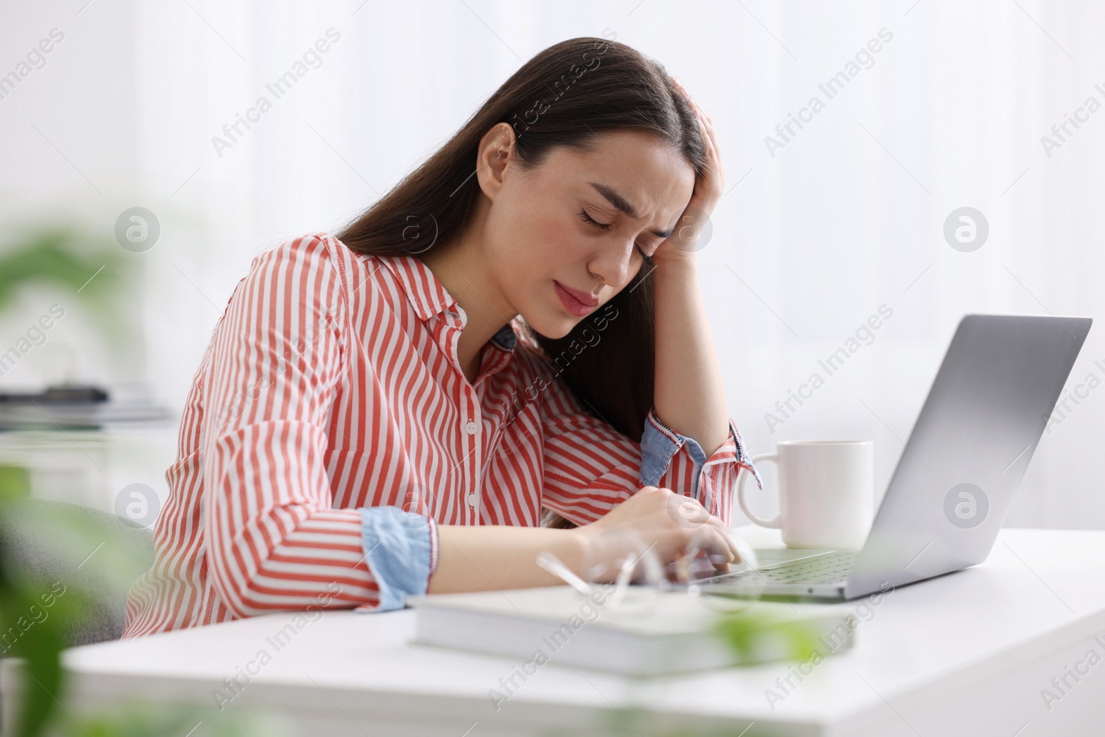 Photo of Woman suffering from headache at workplace in office