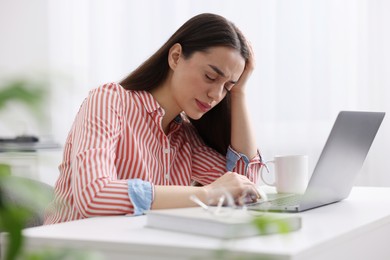 Woman suffering from headache at workplace in office