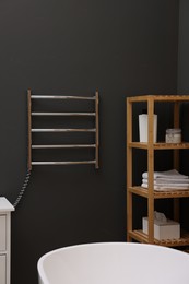 Photo of Stylish bathroom interior with heated towel rail and shelving unit