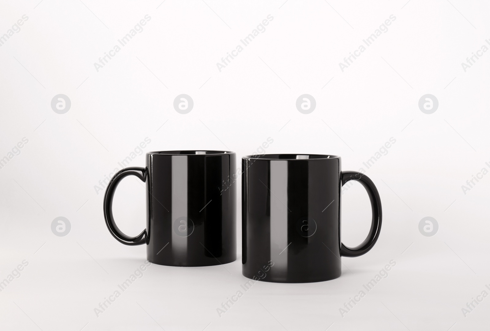 Blank black ceramic mugs on light background Photo of Blank black ceramic mugs on light background