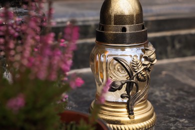 Grave lantern with candle on granite surface at cemetery, closeup