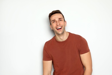 Portrait of handsome man laughing against light background