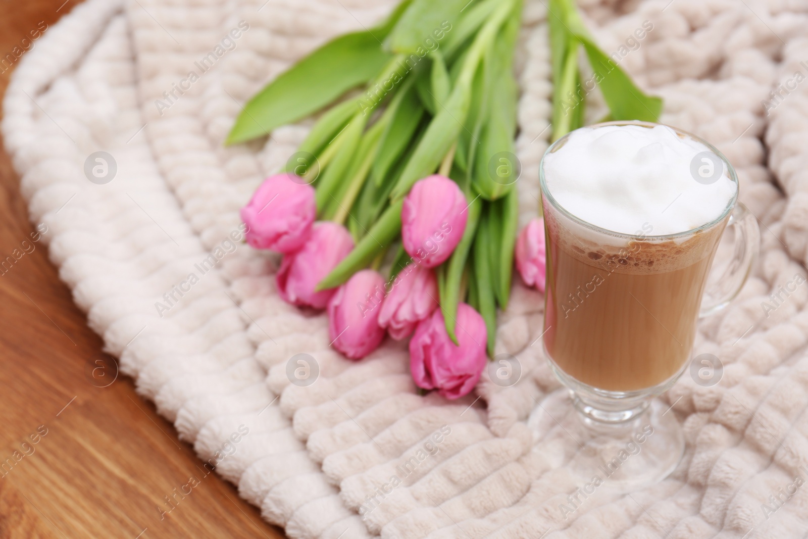 Photo of Glass of delicious cocoa and pink tulips on light blanket, space for text