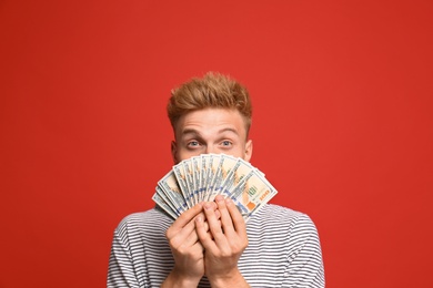 Portrait of surprised lottery winner with money on red background