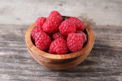 Tasty ripe raspberries in bowl on wooden table