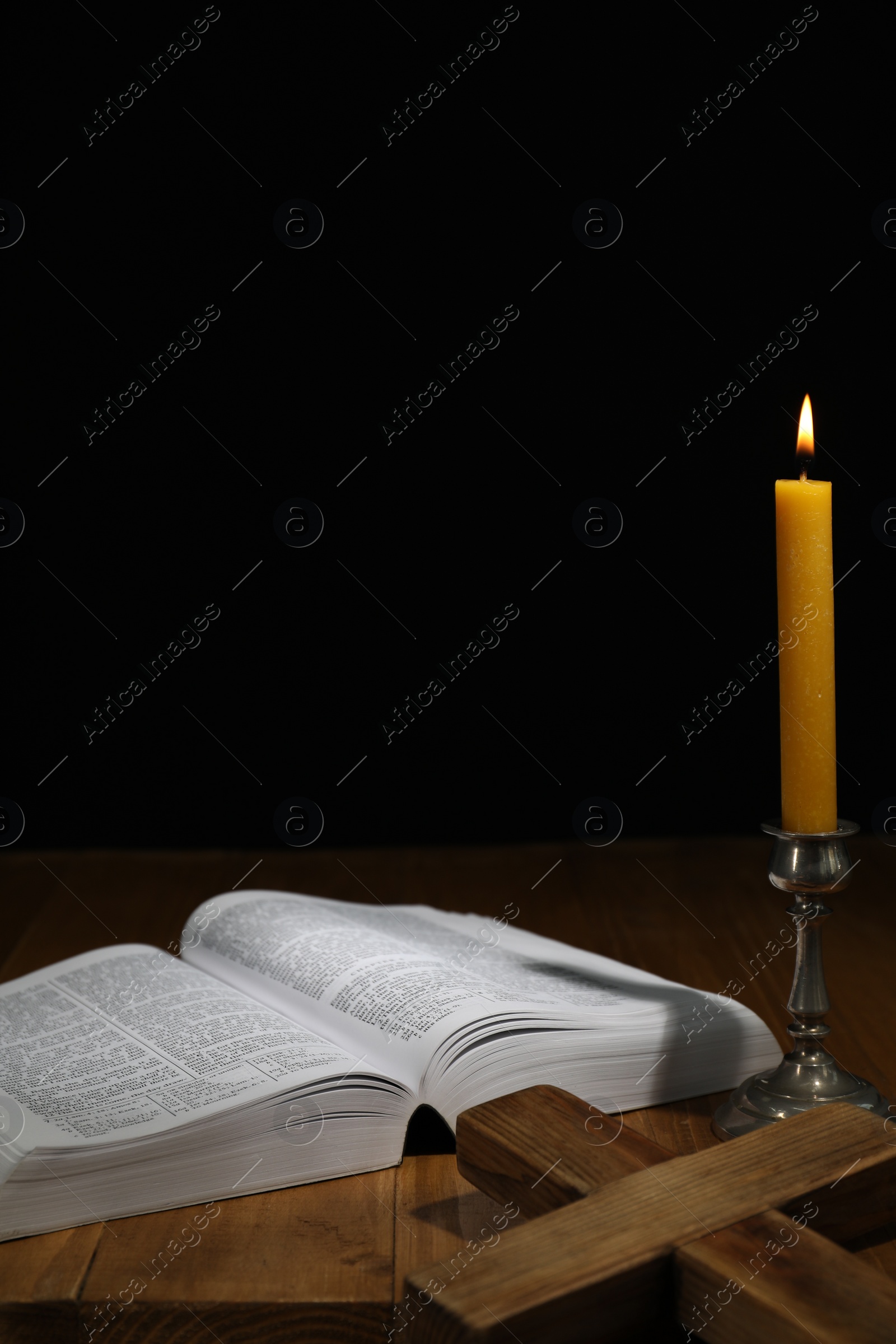 Photo of Bible, cross and church candle on wooden table, space for text