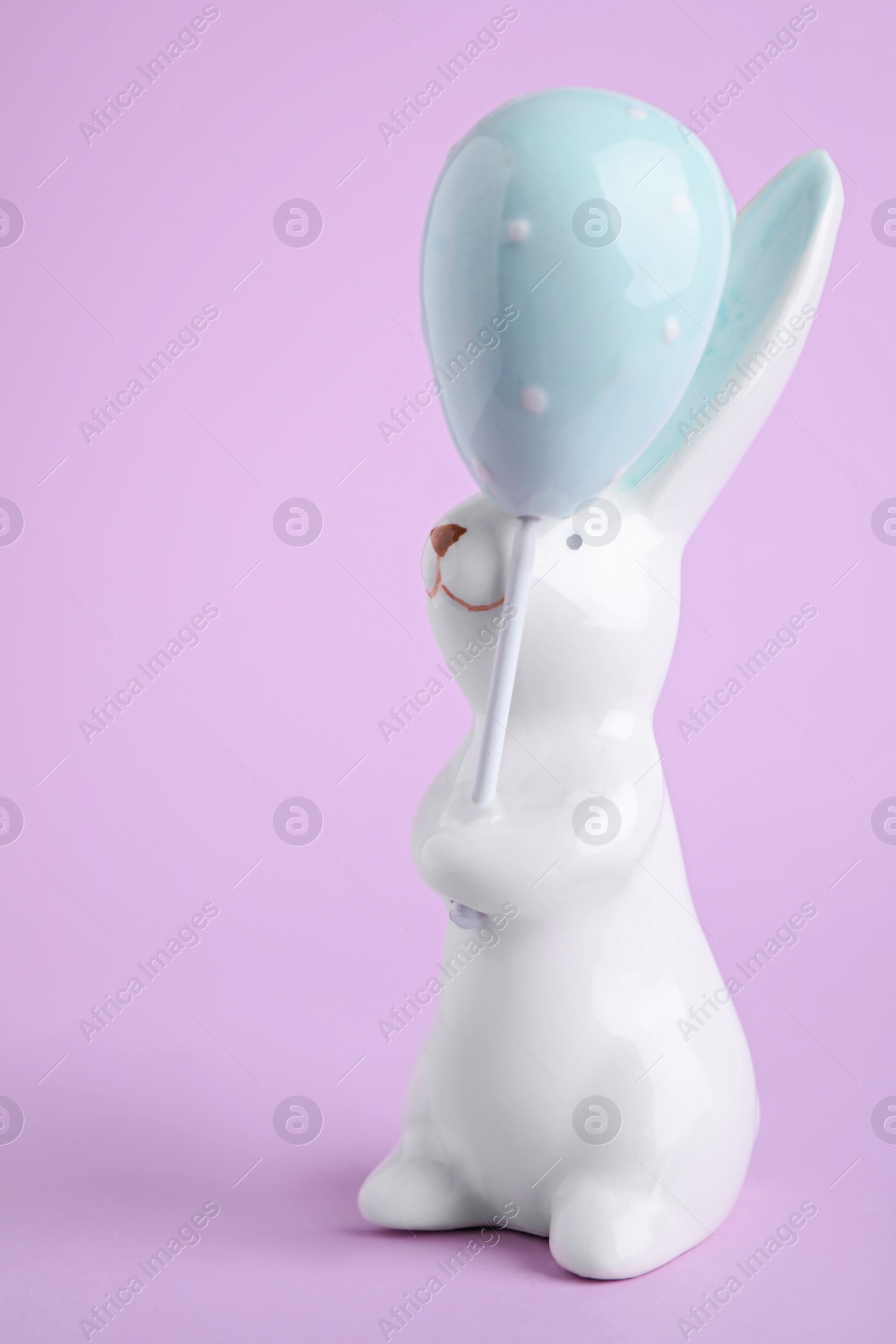 Photo of Bunny ceramic figure as Easter decor on violet background