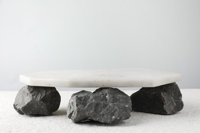 Photo of Presentation for product. Marble podium and stones on grey background. Space for text