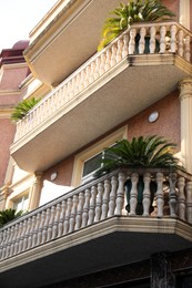 Photo of Exterior of beautiful building with balconies and palm tree outdoors, low angle view