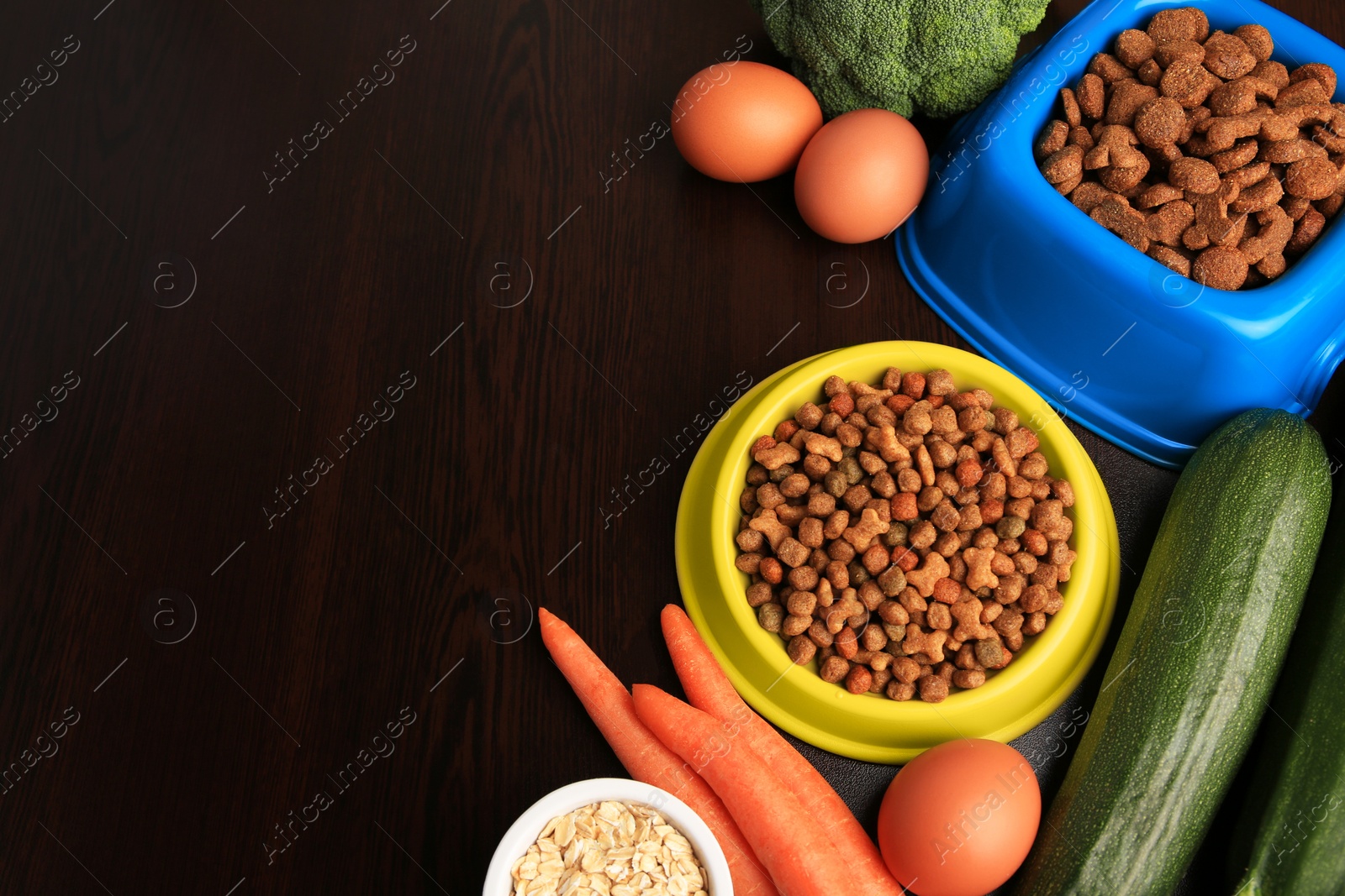Photo of Dry pet food and products on wooden background, above view. Space for text