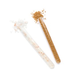 Photo of Glass tubes with pink himalayan salt and mustard seeds on white background, top view