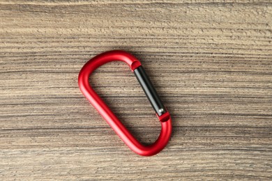 Photo of One metal carabiner on wooden table, top view