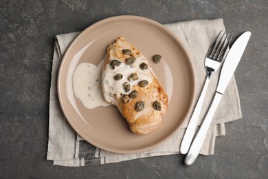 Photo of Delicious chicken fillet with capers and sauce served on grey table, flat lay