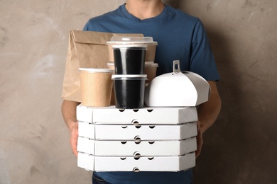 Courier with stack of orders on beige background. Food delivery service