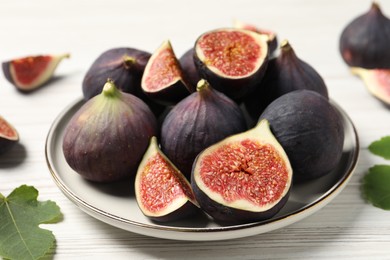 Whole and cut ripe figs on white wooden table, closeup