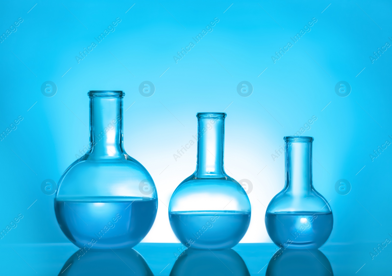 Photo of Laboratory glassware with liquid on color background. Solution chemistry