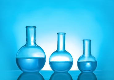 Photo of Laboratory glassware with liquid on color background. Solution chemistry