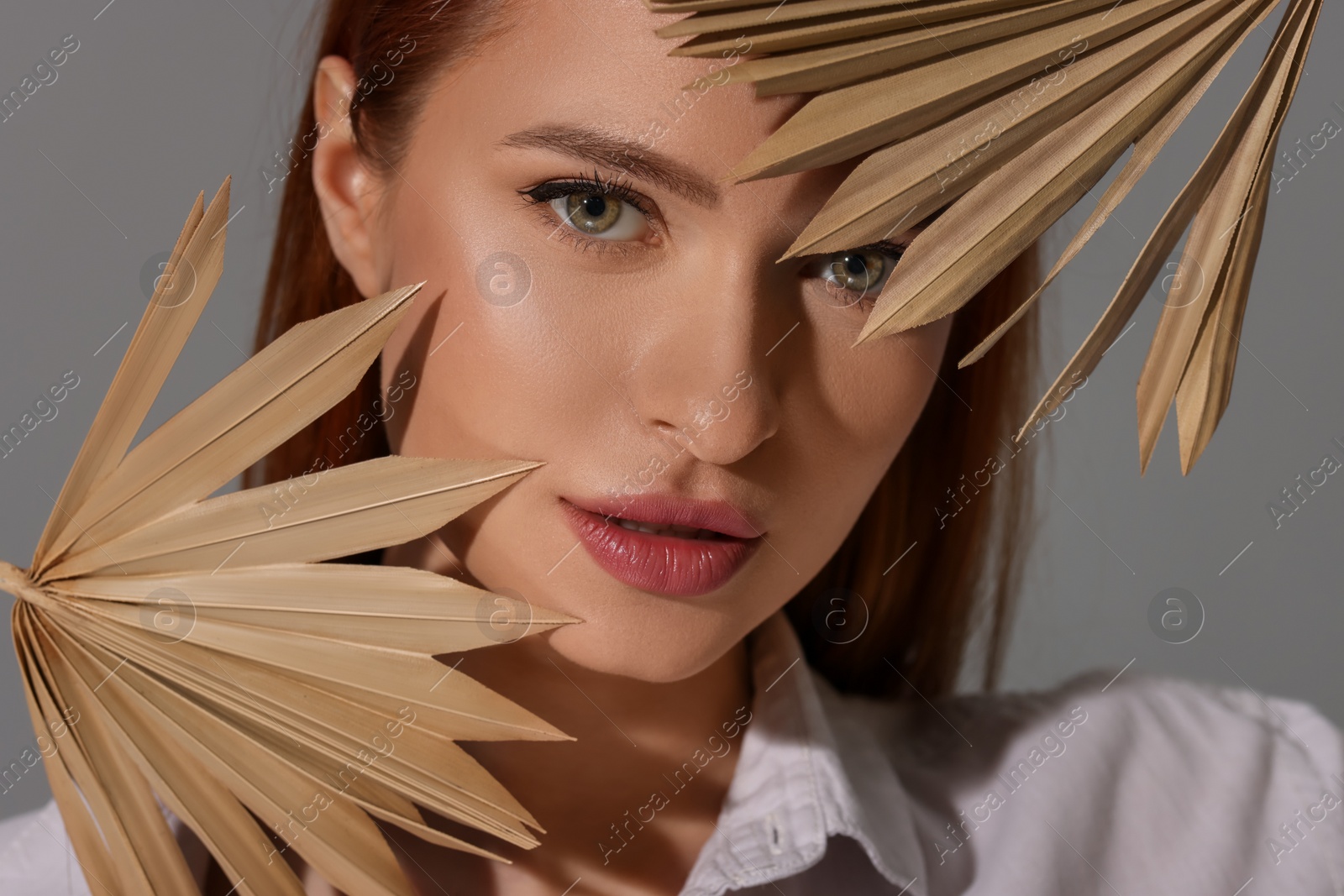 Photo of Beautiful young woman with decorative leaves on gray background, closeup