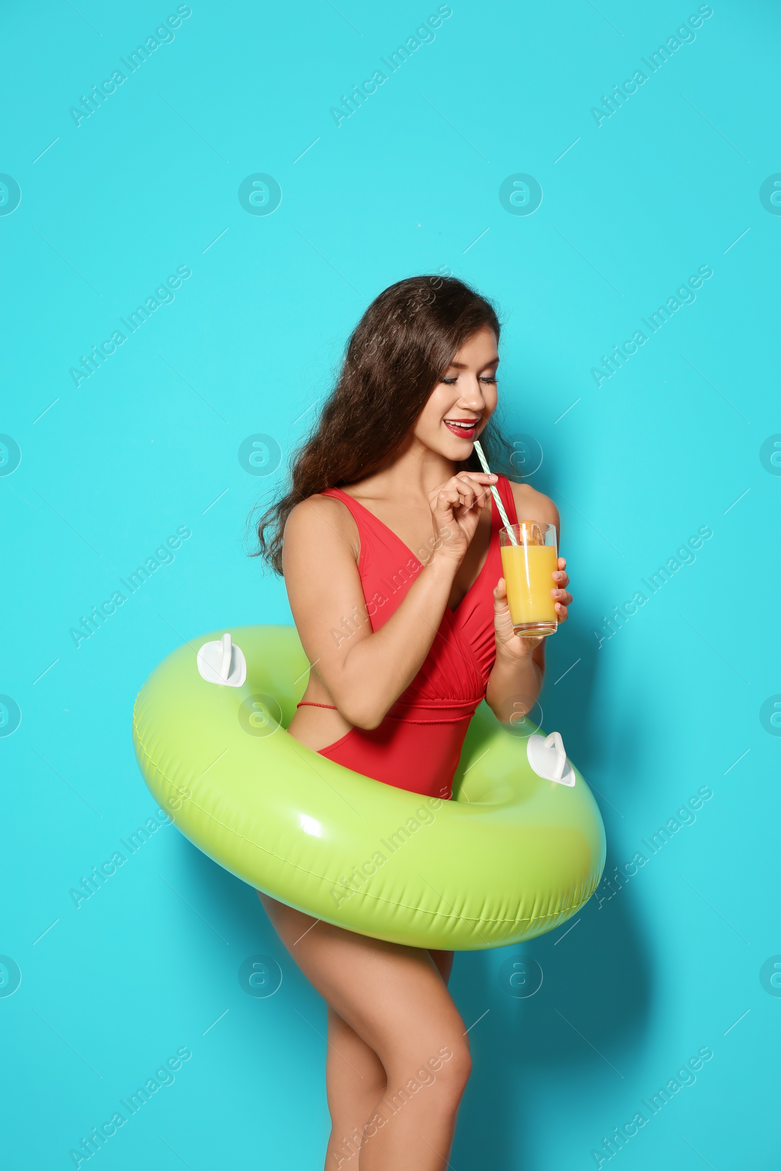 Photo of Beautiful young woman with inflatable ring and glass of cocktail on color background