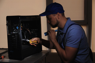 Repairman with flashlight fixing system unit indoors