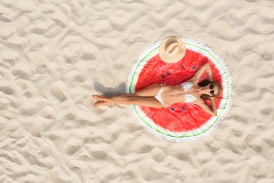 Woman sunbathing on round beach towel at sandy coast, aerial view