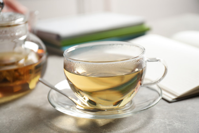 Photo of Tasty hot green tea in cup on grey table, closeup