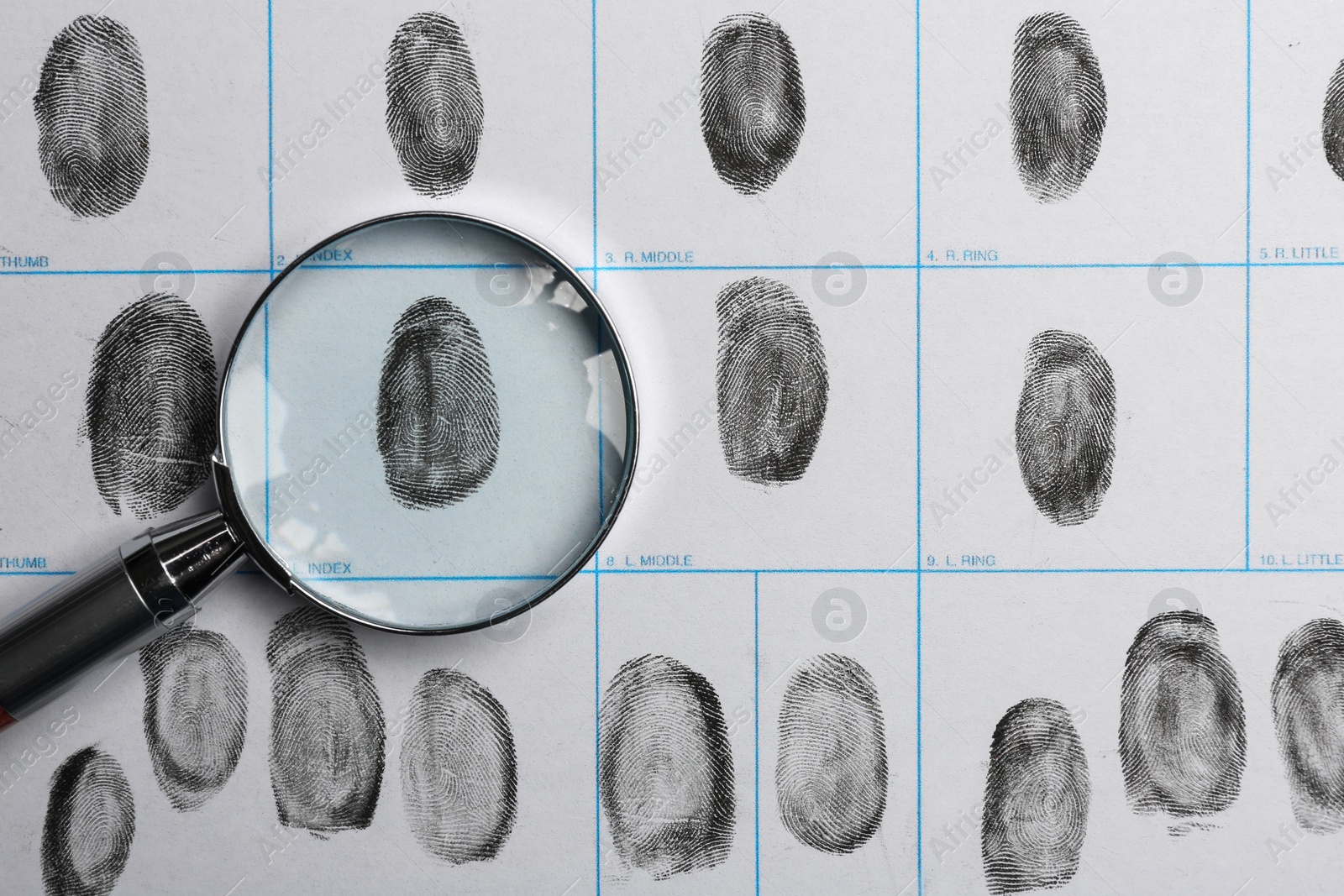 Photo of Magnifying glass and criminal fingerprint card, top view