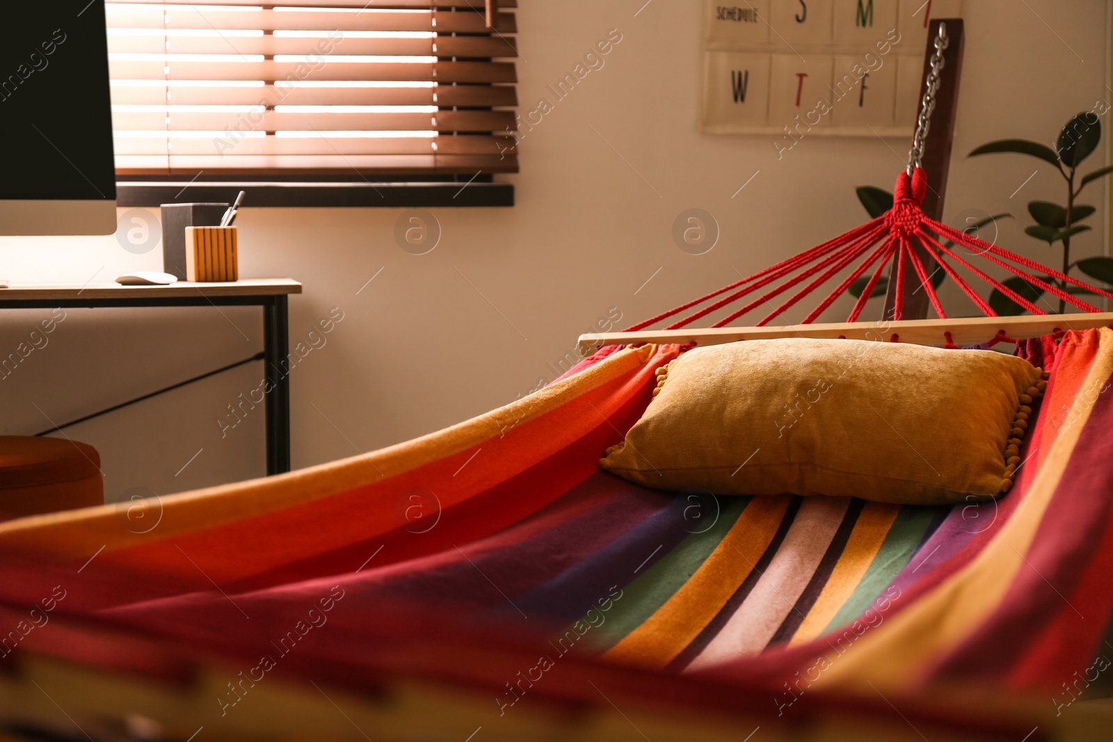 Photo of Colorful hammock with soft pillow indoors, closeup