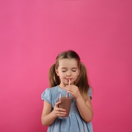Photo of Cute little child drinking tasty chocolate milk on pink background