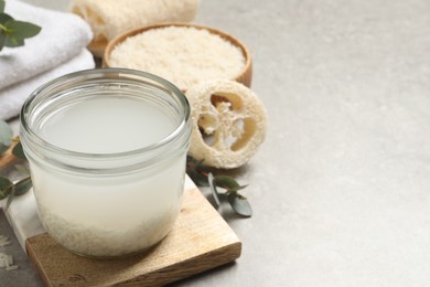 Photo of Glass jar with rice soaked in water on light grey table. Space for text