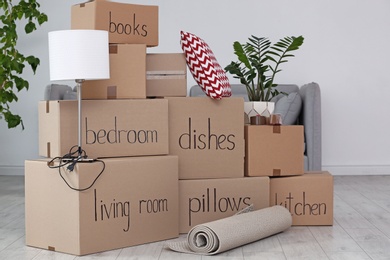 Photo of Pile of moving boxes and household stuff in living room