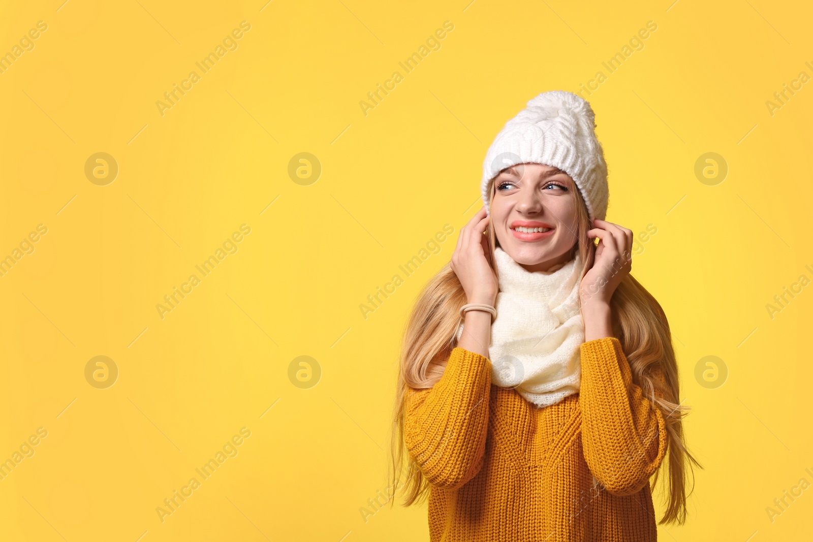 Photo of Portrait of emotional young woman in stylish hat, sweater and scarf on color background, space for text. Winter atmosphere