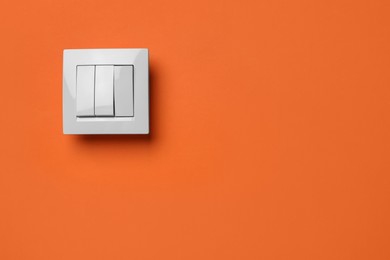 Photo of White light switch on orange background. Space for text