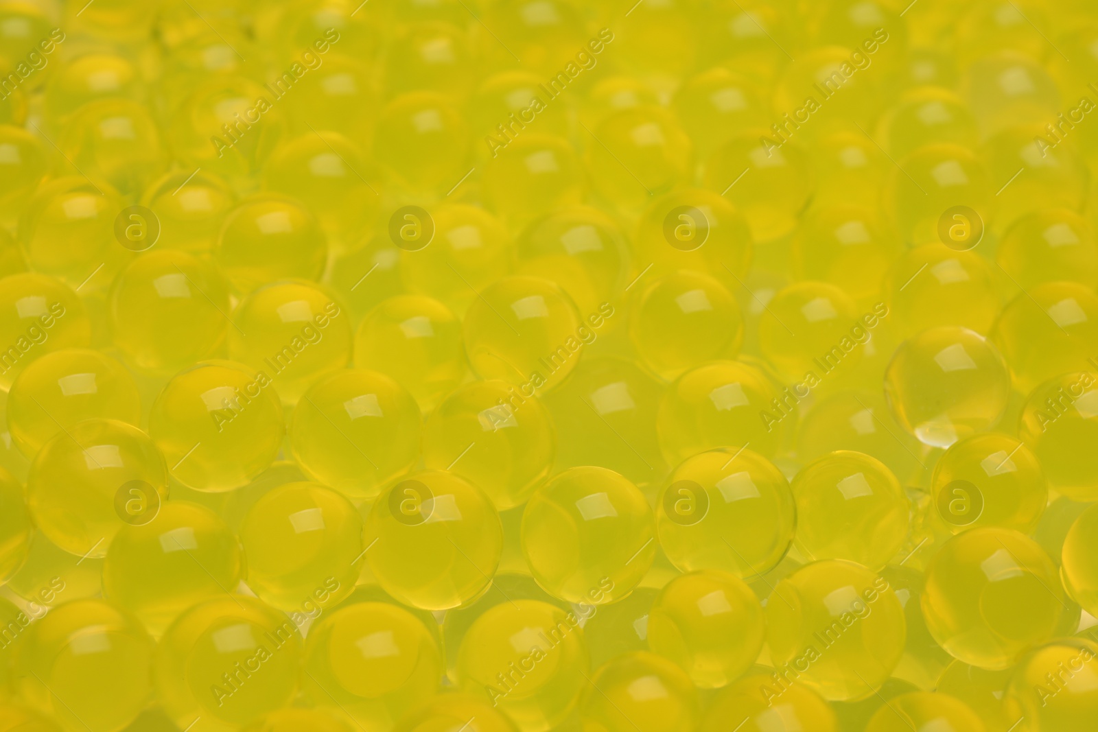 Photo of Closeup view of yellow vase filler as background. Water beads